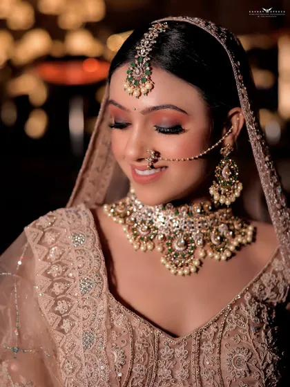 A close-up portrait focusing on the bride's serene expression and beautiful makeup. The soft bokeh background adds a dreamy quality to this elegant shot.