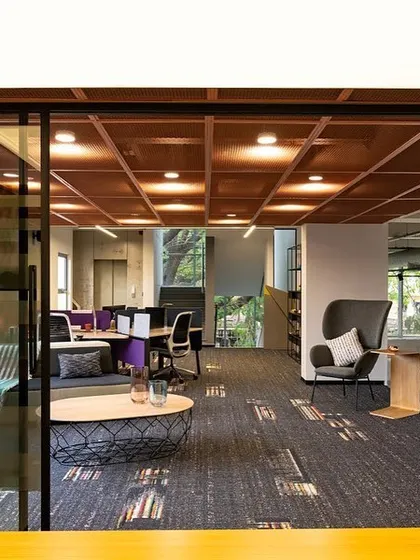 This view shows the conference room in context with the adjoining breakout space. The lighting design creates a clear distinction between the focused task area of the meeting room and the more relaxed ambient lighting of the lounge.