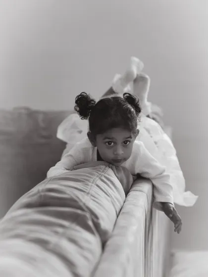 Sometimes the quietest moments are the most powerful. This is a gentle portrait of a young girl peering over the couch, a candid moment of curiosity captured during an in-home family session.