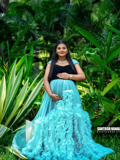 A wide shot showing how the vibrant blue gown contrasts beautifully with the lush greenery. We compose our shots to make the subject and their attire stand out naturally.