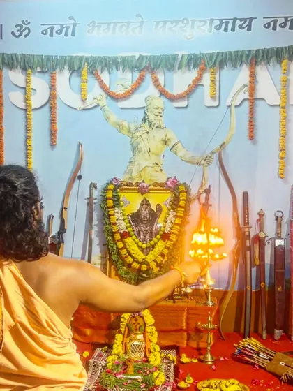 Performing the aarti with a sacred lamp during the Ayudha Puja. The light is offered to the deity and the weapons, symbolizing the illumination of wisdom and skill.
