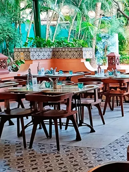 Another view of the outdoor dining area in Goa, showcasing the custom-designed wooden chairs and the decorative tilework on the planters that add to the resort's unique charm.