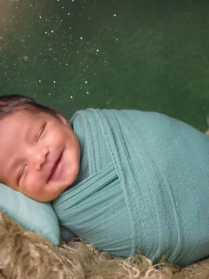 That heart-melting newborn smile. This little one is happily dreaming, swaddled snugly in a cozy nest. Capturing these fleeting smiles is what makes newborn photography so special.