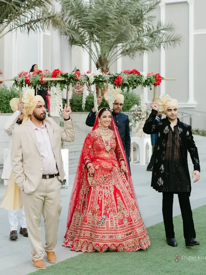 The bride's grand entrance under a beautiful floral 'phoolon ki chadar' held by her brothers.