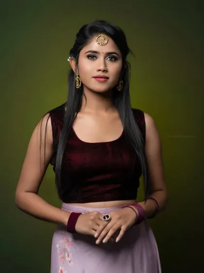A studio portrait in a traditional lehenga, perfect for a makeup artist's portfolio. The green background provides a nice contrast.