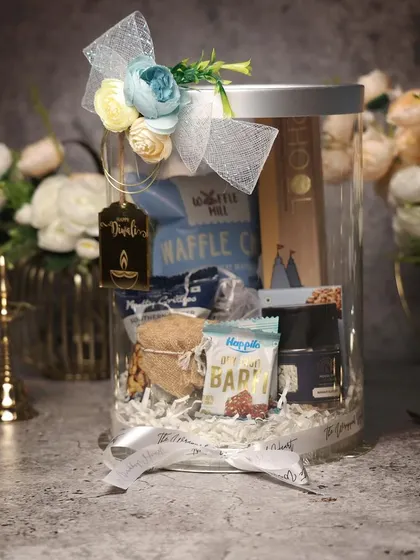 Another modern take on Diwali gifting. This acrylic jar hamper is filled with a curated selection of snacks and goodies, finished with a beautiful floral-tied ribbon.