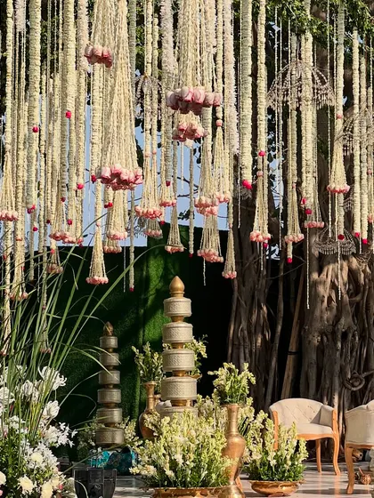 A closer look at the mandap built around a tree, with hanging floral strings and traditional brass elements creating a sacred space.