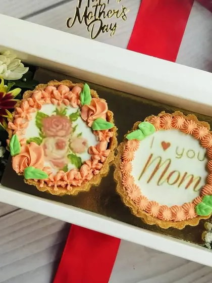 The two mini tarts for Mother's Day are shown here nestled between fresh green and yellow chrysanthemums, creating a beautiful color contrast.