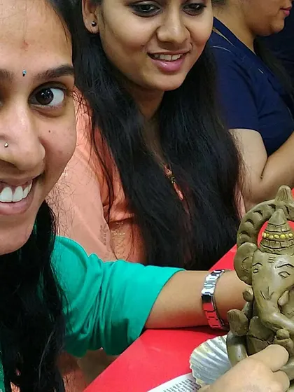 The pride in finishing your own piece of art is universal. A participant from a corporate event proudly shows off the detailed clay Ganesha she sculpted during our workshop.