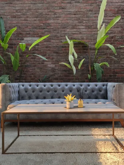 A cozy seating arrangement in the lounge, where the softness of the velvet sofa contrasts with the rustic exposed brick wall behind it.