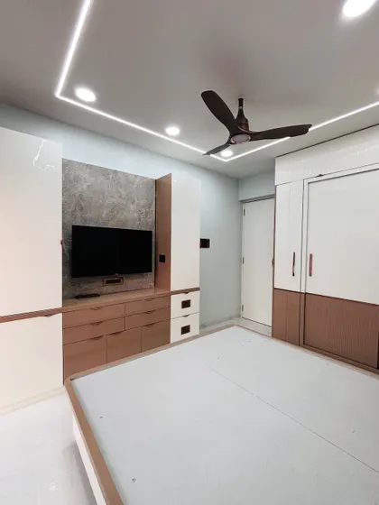 A full view of the bedroom, showing the TV unit on one wall and the sliding wardrobe on the other, creating a balanced and functional layout.