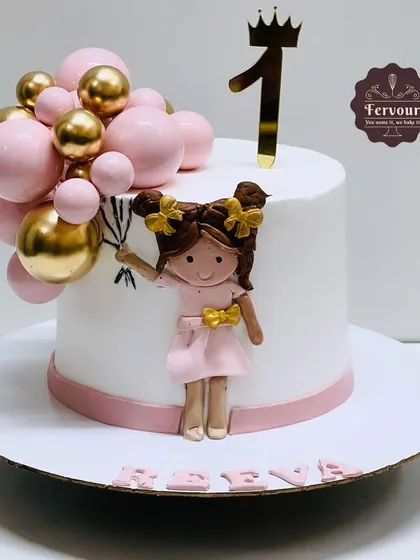 A chic first birthday cake featuring a hand-molded girl holding a bouquet of pink and gold balloons. The design is simple, elegant, and perfect for a stylish little one's party.