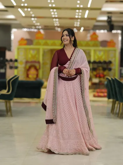 A solo shot capturing the joy of the day. The V-neck blouse and sheer sleeves add a modern touch to the traditional lehenga silhouette.