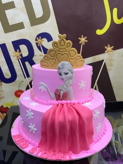 A 4kg two-tiered Frozen cake in pink, featuring an edible image of Elsa, a fondant dress, and a golden tiara.