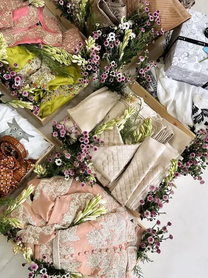 An overhead view of a trousseau collection decorated with exotic fresh flowers. We use fragrant tuberoses and delicate purple daisies to create a lush, garden-like feel around each gift tray, adding a touch of natural elegance.