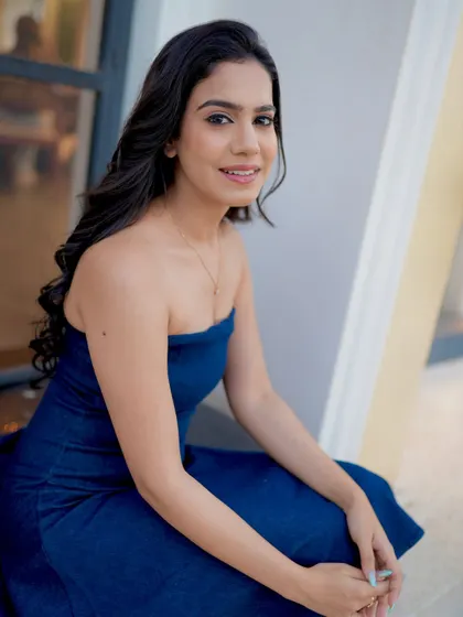 A seated pose in the blue dress, looking friendly and engaging.