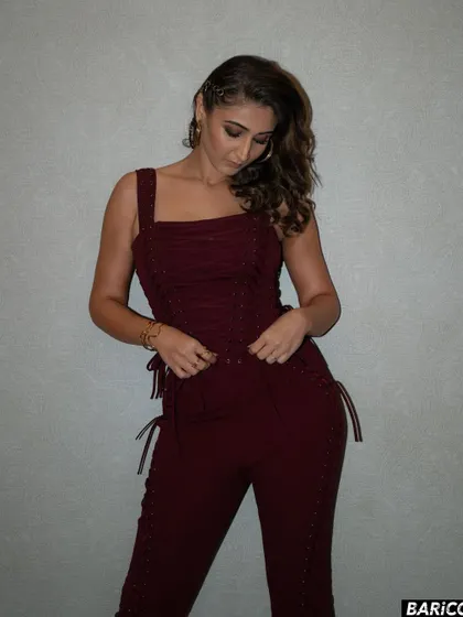 A candid moment showing the details of the custom jumpsuit. The lace-up sides add a unique, edgy touch to the overall look.