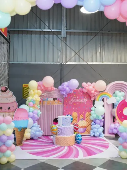 Another view of the spectacular candy-themed photo booth area, framed by a massive pastel balloon arch. It's the perfect spot for birthday photos.