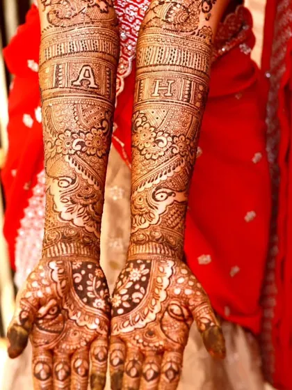 A detailed bridal design featuring the couple's initials, "A" and "H", prominently on the arms. The patterns are intricate and filled with paisley and floral motifs.