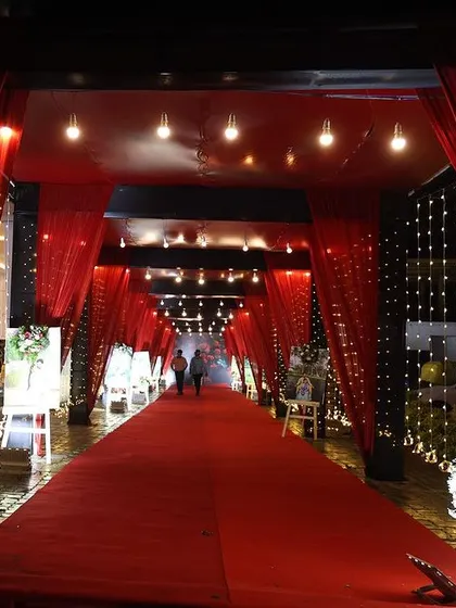 I created this dramatic red carpet entrance walkway for a reception. The entire passage was draped in red fabric with sparkling fairy lights, making the guests feel like they are walking into a movie premiere.