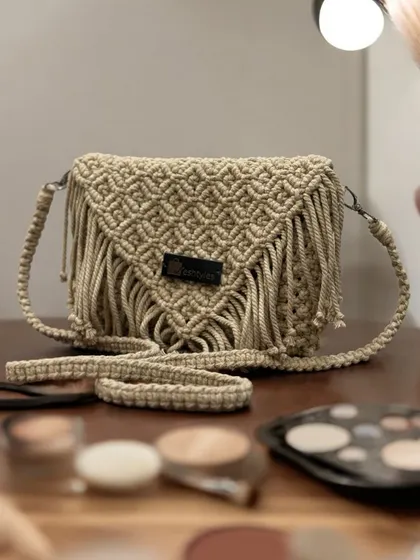 This beige fringed sling bag is a classic. It's pictured here with some makeup essentials, showing how it's the perfect little bag for your daily adventures.