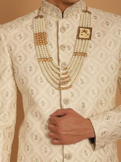 The centerpiece of a groom's attire. This detailed shot highlights the exquisite pearl and gold necklace that perfectly complements our sherwanis.