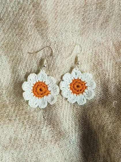 Simple and sweet, these little daisy earrings are perfect for everyday wear. The white petals and orange center are crocheted from soft cotton thread.
