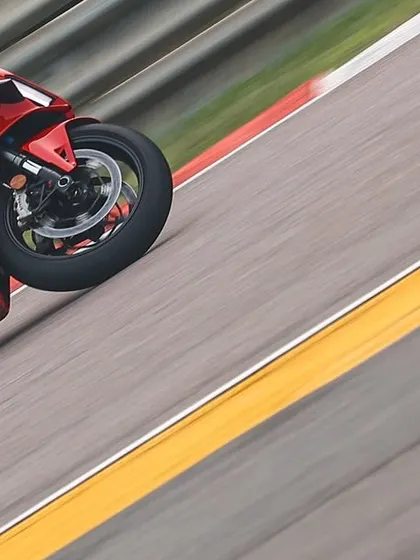 A pair of red Ducati superbikes fly down the track in a blur of motion, capturing the raw speed of an open track day.