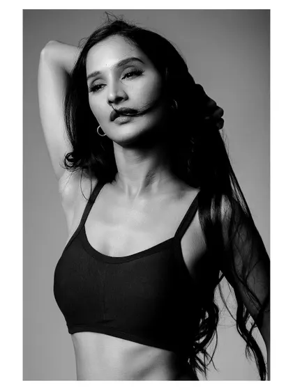 A black and white portrait of a model in activewear. The wind-blown hair and strong pose create a dynamic and powerful fitness shot.