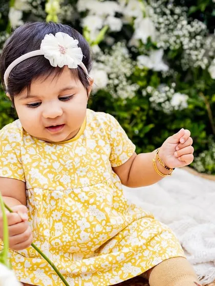 A sweet baby girl holding a flower, captured in timeless black and white.