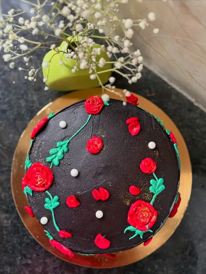 A rich Dutch truffle cake decorated with a beautiful pattern of hand-piped red roses and green leaves.