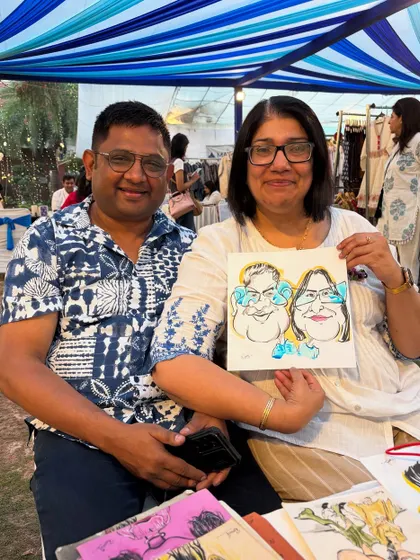 A couple enjoying their time at a festival and getting a caricature done.