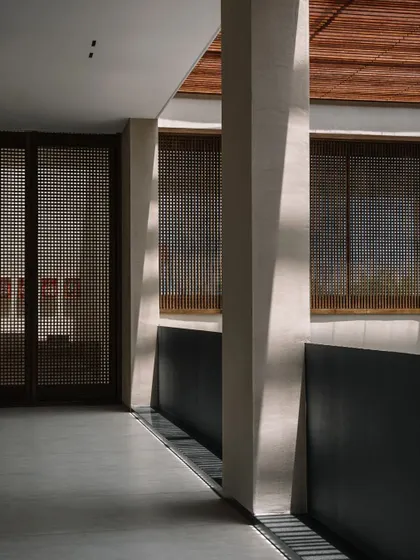 The corridors are designed to be experiences in themselves, with changing patterns of light and views of the central courtyard. The use of wooden screens provides privacy while maintaining a connection to the outdoors.