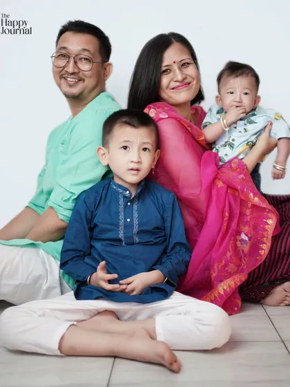 A warm family portrait showcasing traditional attire. The photo captures four family members sitting together, sharing smiles and a sense of togetherness.