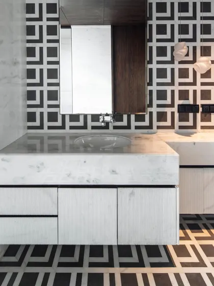 The master washroom features a fluted vanity crafted from the same marble as the walls and floor. Bocci lights from Lightbox cast a warm glow, creating a sanctuary of comfort and style.