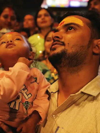 A father holds his child up to see the drone show in Varanasi. Our shows are for all ages, creating memories that families can share for a lifetime.