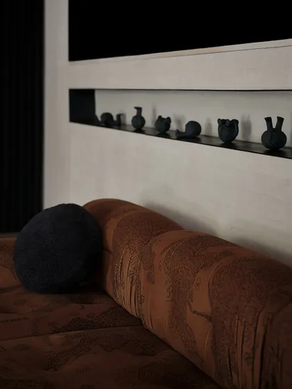A small, curated collection of black ceramic objects sits in a niche above the living room sofa. These subtle details add personality and an artistic touch to the space.
