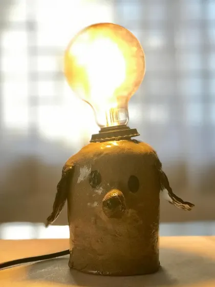 A close-up of the charming dog lamp, glowing warmly. It's amazing to see how a simple clay form, a glaze, and a lightbulb can come together to create something with so much personality.