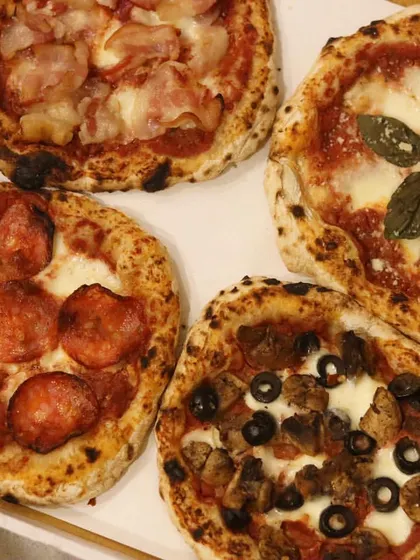 Another look at my party box of four mini pizzas. This assortment includes a mini Margherita, a pepperoni, a mushroom and olive, and a ham pizza, offering something for everyone.