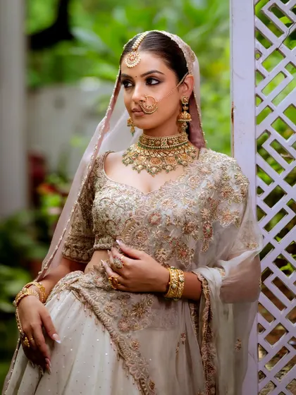 A beautiful portrait of the bride in her stunning off-white lehenga. The makeup is glamorous yet soft, with a focus on her expressive eyes and a flawless complexion.