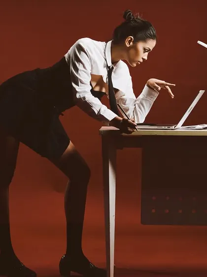 A corporate-themed shot with a fashion edge. The lighting is cinematic, using a single lamp as a practical light source and a strobe to create the sharp, defined shadows.