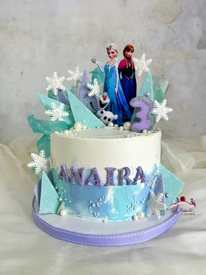 A cool Frozen-themed cake featuring Elsa and Anna toppers, surrounded by icy blue and purple chocolate shards and delicate snowflakes.