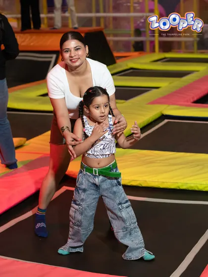 A mother helps her little one find her balance on the trampoline. It's a perfect place for shared moments of fun.