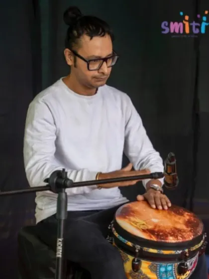 A percussionist leads a drum jam session, bringing children and grandparents together in rhythm. Music is a universal language that connects generations.