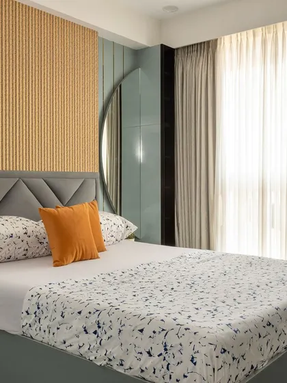 This bedroom uses a combination of textures, with a grey tufted headboard set against a fluted wooden panel wall, creating a modern and sophisticated look.