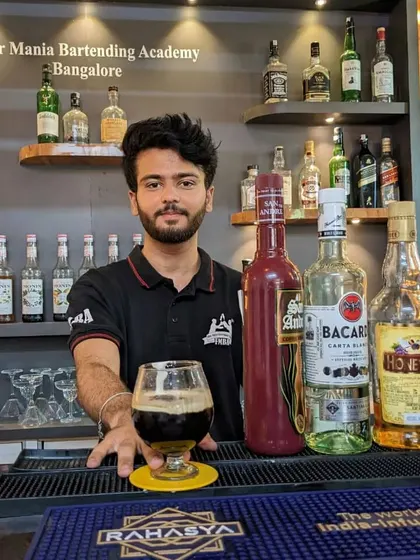 A bartender presenting a dark, rich cocktail, showcasing the variety of spirits we work with, including rum and brandy.