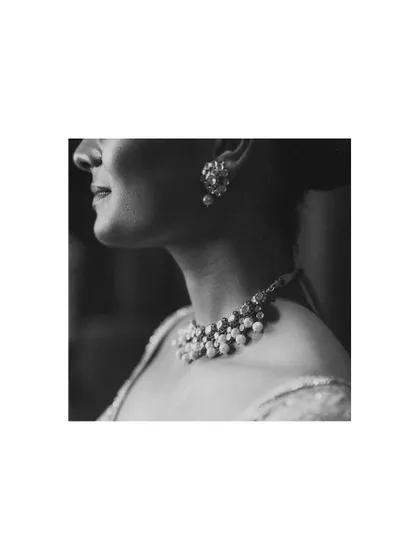 A close-up, black and white shot of the bride's elegant necklace and earring, highlighting the beauty of her wedding jewelry.