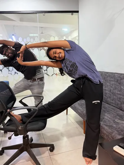 An employee at Skills Outsource enjoys a supported side stretch using her office chair. This pose helps lengthen the side body and improve posture.
