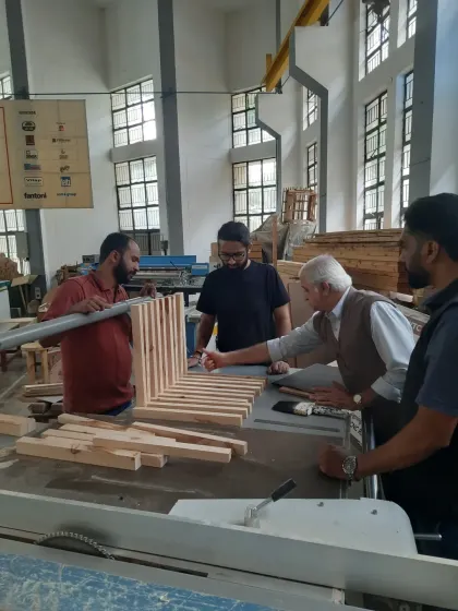 Teamwork in the workshop. Students collaborate on a project at the table saw under the watchful eye of their trainer, learning how to manage larger pieces of material.