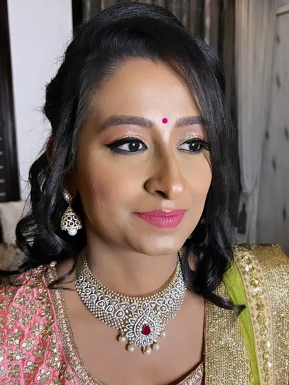 A beautiful reception look for a family wedding. The client is wearing a pink and green lehenga, complemented by glittery eye makeup and a pink lip.